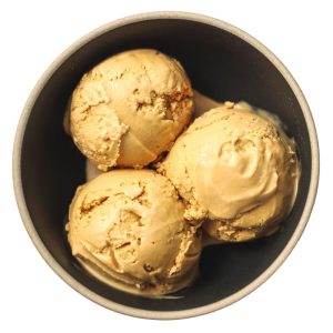 Three scoops of caramel ice cream in a bowl.