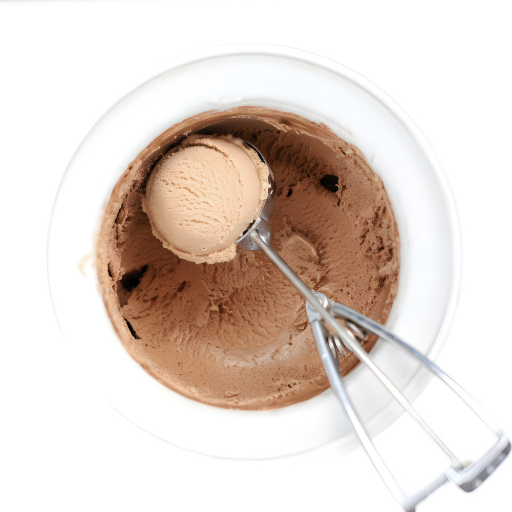 Overhead view of chocolate-only ice cream made with egg-yolks in a white container with an ice cream scoop lifting one scoop.